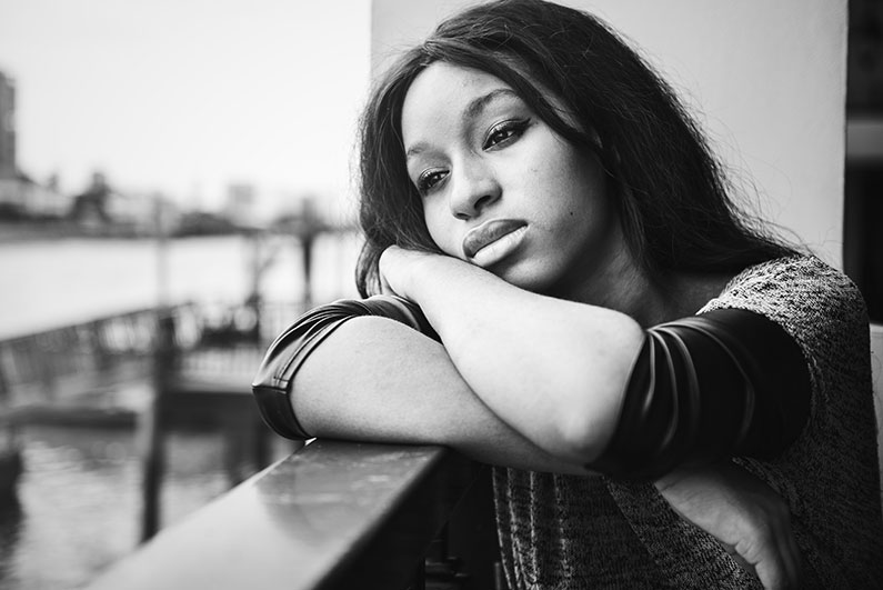 Black and white picture of woman with her head resting on hand rail