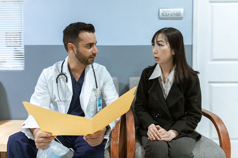 A patient discusses her case with her doctor as he looks at her file.