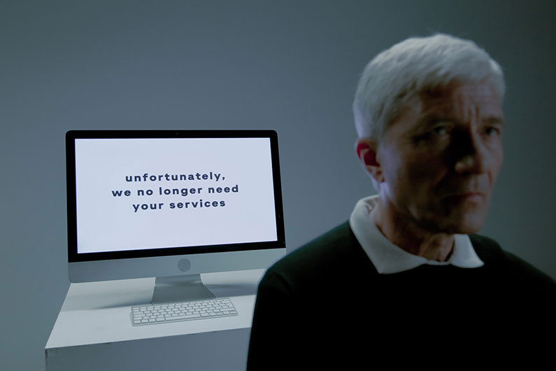 Elderly man and screen with information that his services are no longer needed.