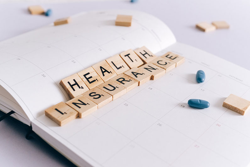 Scrabble tiles on a planner spell out the words health insurance