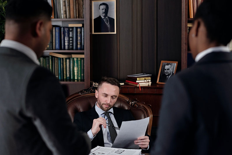 An arbitrator sitting at a desk listens to the two parties while examining a document.