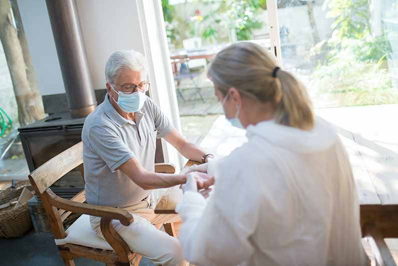 An elderly man is being examined by a woman who appears to be a medical professional.