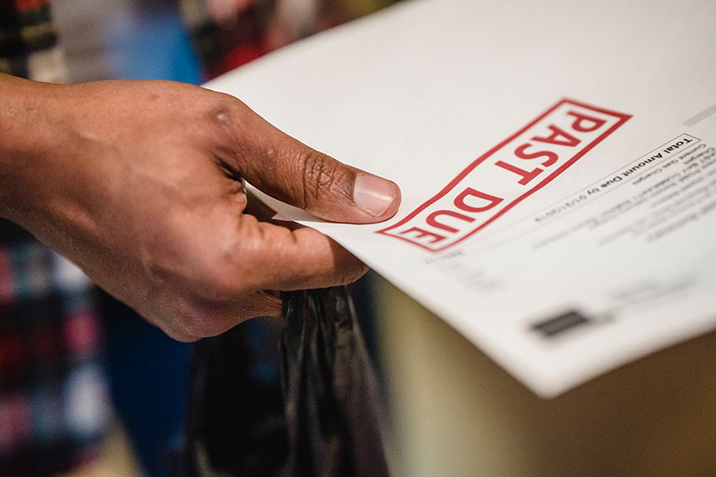 Closeup of a hand holding a notice stamped Past Due. 