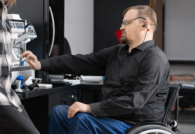 An employee in a wheelchair using assistive devices