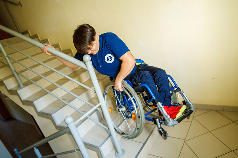 A person in a wheelchair struggling down a flight of stairs